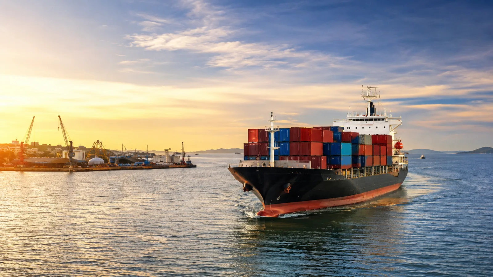Container vessel leaving port at sunset